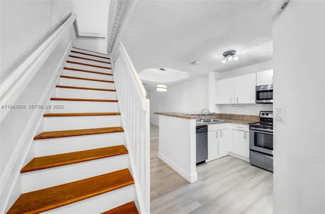 a open kitchen with white cabinets and white appliances