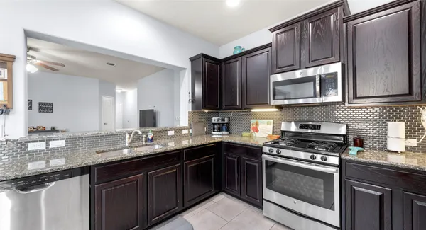 a kitchen with granite countertop wooden cabinets stainless steel appliances and a sink