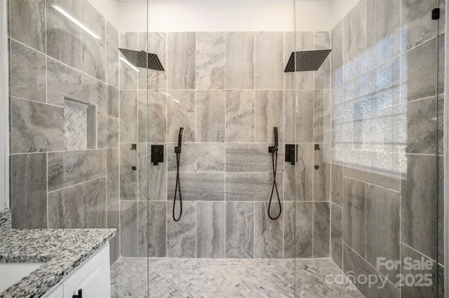 a bathroom with a granite countertop shower a sink and a mirror