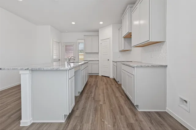 a kitchen with a sink dishwasher and white cabinets with wooden floor