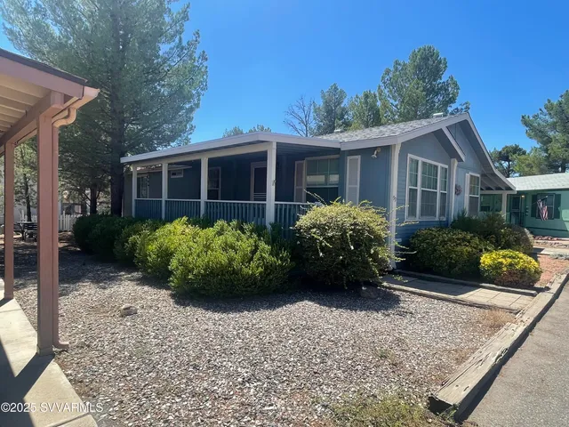 a view of a house that has a bunch of plants and large trees