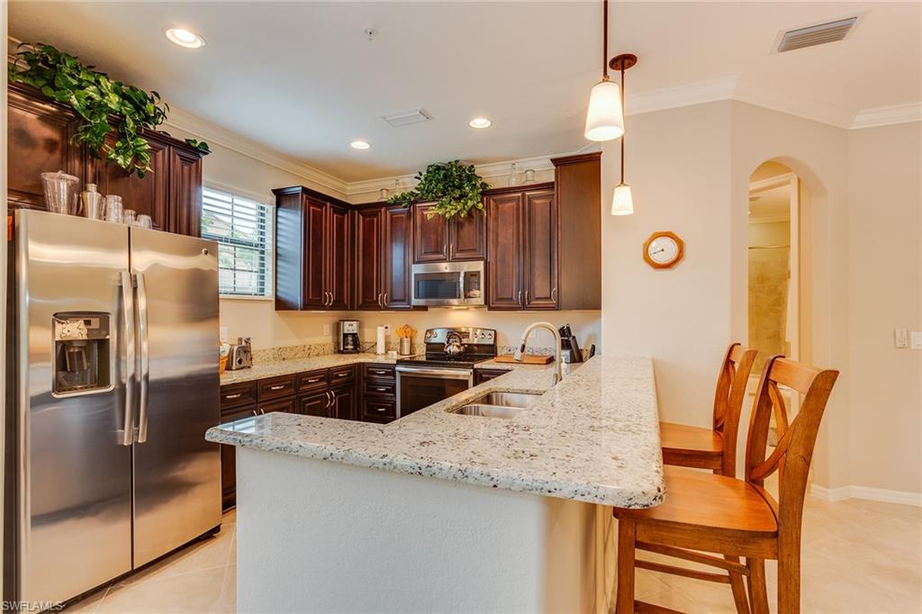 9082 Capistrano Street North, Unit 485 Naples, FL 34113 - Photo 6 of 16 a kitchen with granite countertop kitchen island a counter space a sink appliances and cabinets