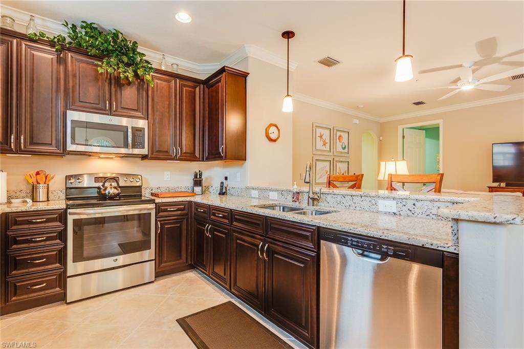 9082 Capistrano Street North, Unit 485 Naples, FL 34113 - Photo 7 of 16 a kitchen with stainless steel appliances granite countertop a stove a sink and a microwave