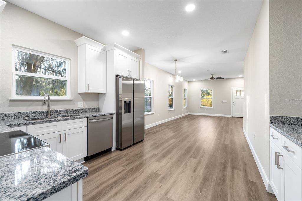 2016 Northeast 3rd Avenue Gainesville, FL 32641 - Photo 2 of 35 a kitchen with granite countertop a refrigerator a sink dishwasher a stove and white cabinets with wooden floor