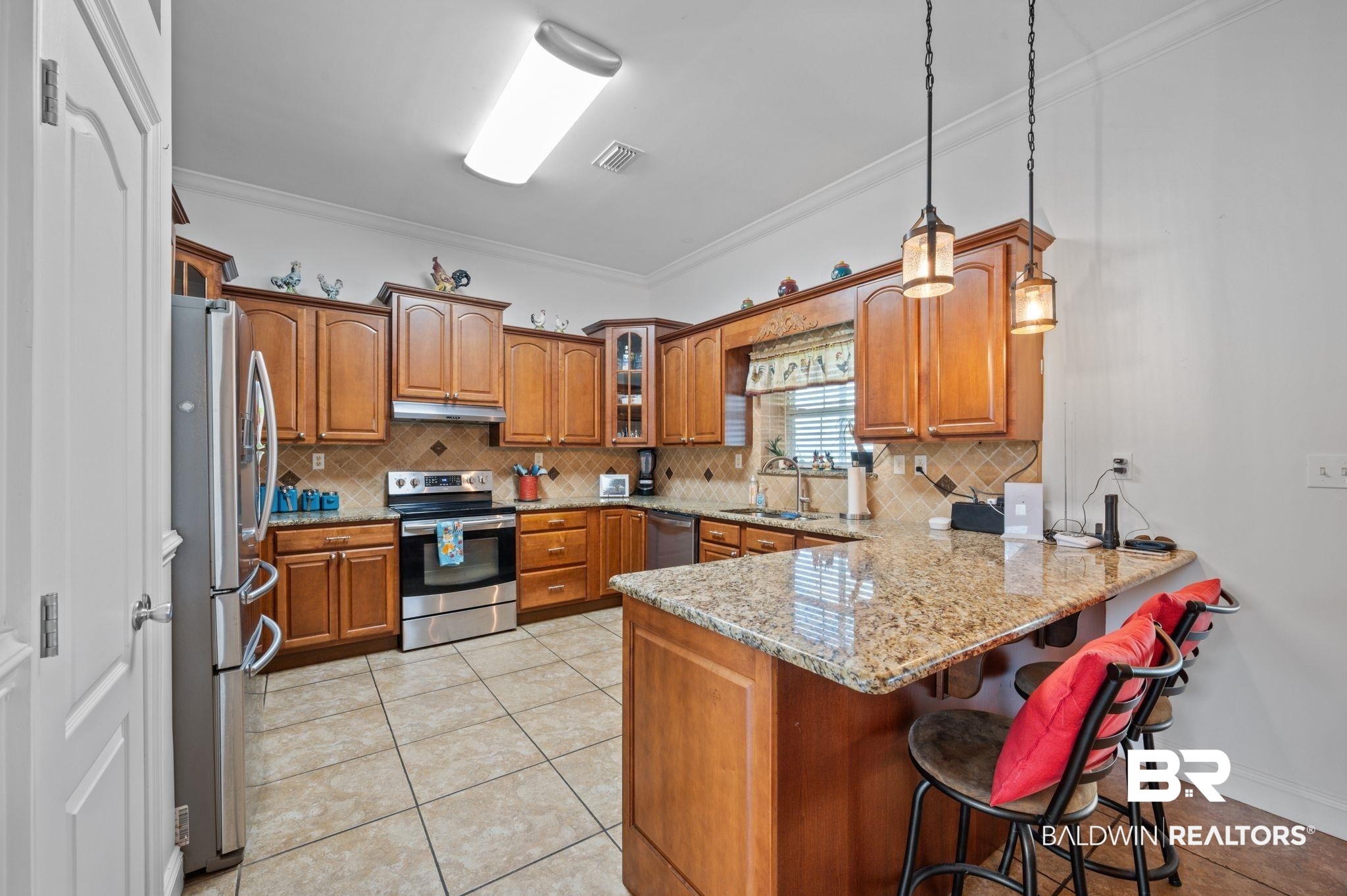 48513 Phillipsville Road Bay Minette, AL 36507 - Photo 13 of 50 Kitchen featuring stainless steel appliances, a peninsula, under cabinet range hood, brown cabinets, and backsplash