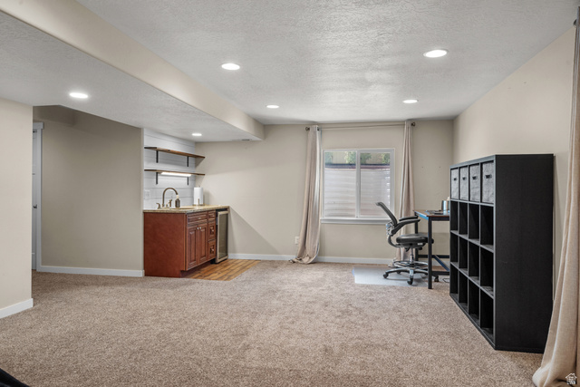 955 Delorean Lane Midvale, UT 84047 - Photo 36 of 47 Spacious room featuring plush carpeting, recessed lighting, and a built-in wet bar with wood cabinetry, a sink, and a beverage cooler