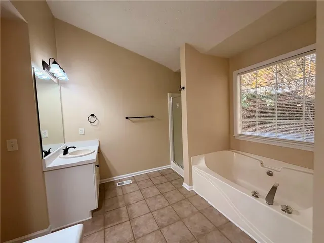 an empty room with chandelier fan and windows