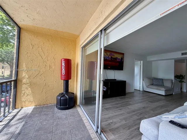 a living room with furniture a flat screen tv and a floor to ceiling window