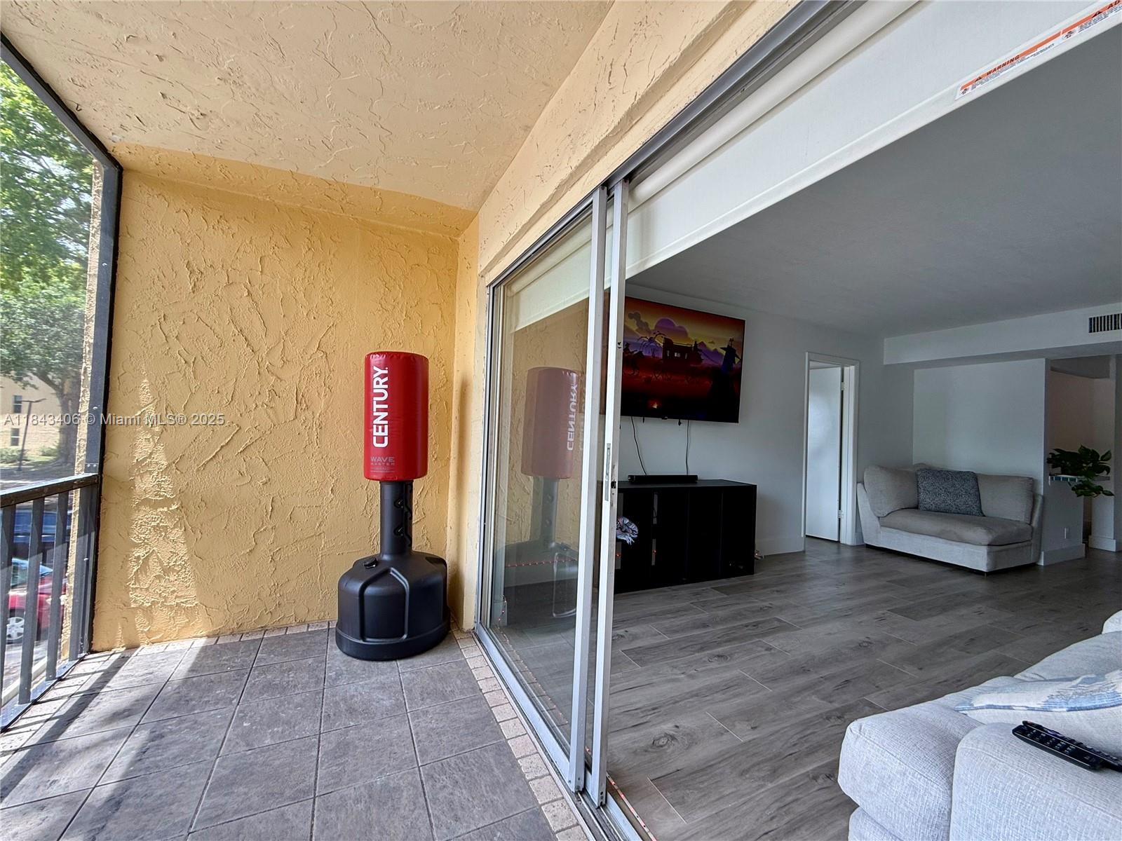 480 Northwest 20th Street, Unit 207 Boca Raton, FL 33431 - Photo 6 of 26 a living room with furniture a flat screen tv and a floor to ceiling window