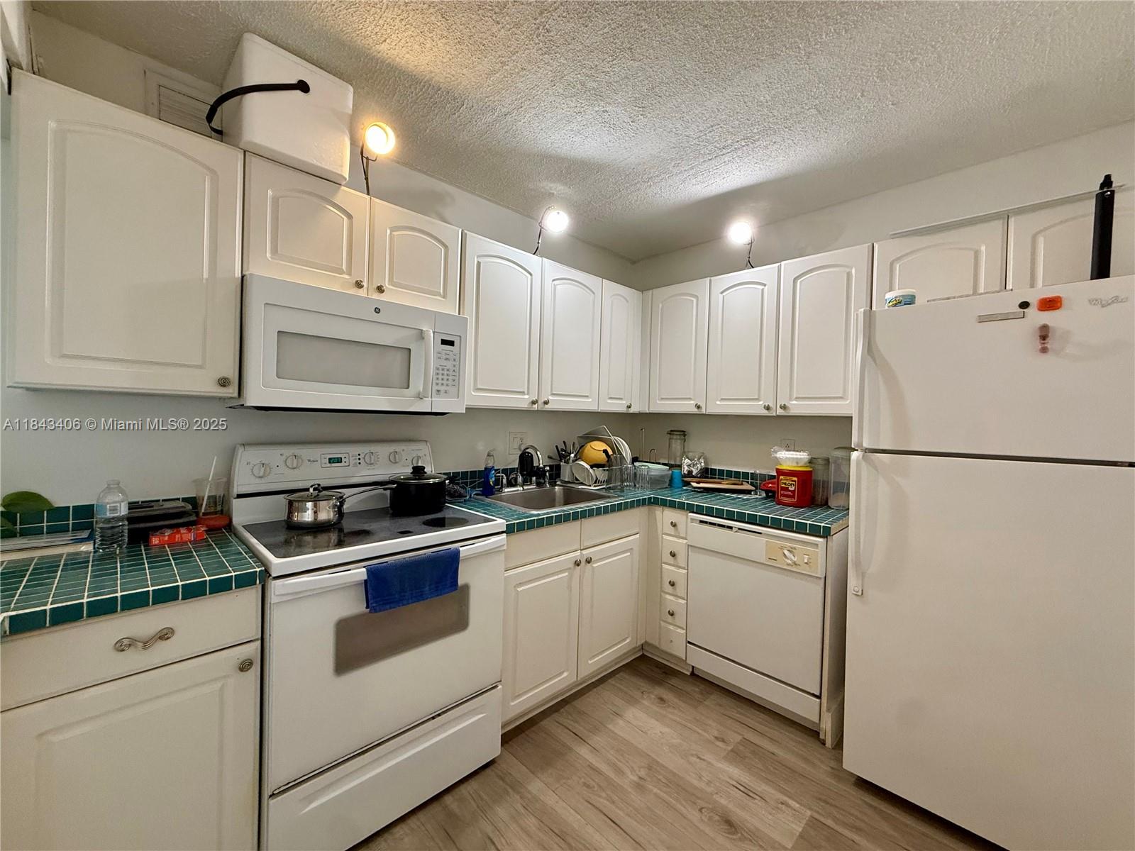 480 Northwest 20th Street, Unit 207 Boca Raton, FL 33431 - Photo 7 of 26 a kitchen with white cabinets and white appliances