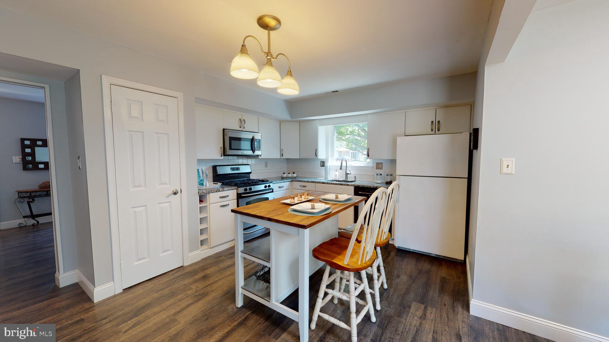 5 Carlton Avenue Evesham, NJ 08053 - Photo 9 of 33 a kitchen with stainless steel appliances granite countertop a refrigerator a stove a microwave oven a dining table and chairs with wooden floor