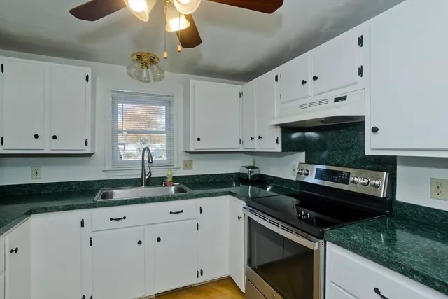a kitchen with granite countertop a sink a stove and cabinets