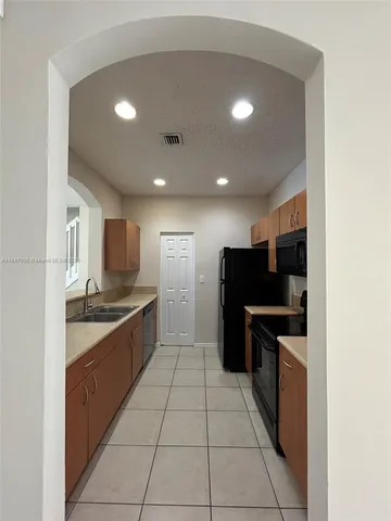 a large kitchen with stainless steel appliances granite countertop a refrigerator and a stove