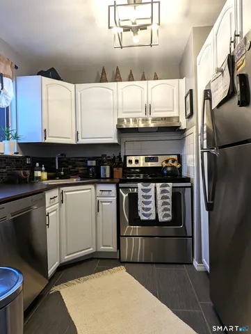 a kitchen with stainless steel appliances kitchen island granite countertop a refrigerator a stove and a sink