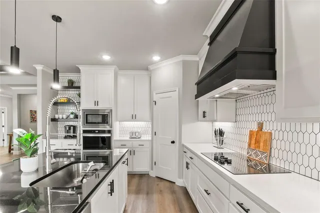 a kitchen with stainless steel appliances kitchen island granite countertop a sink stove and white cabinets