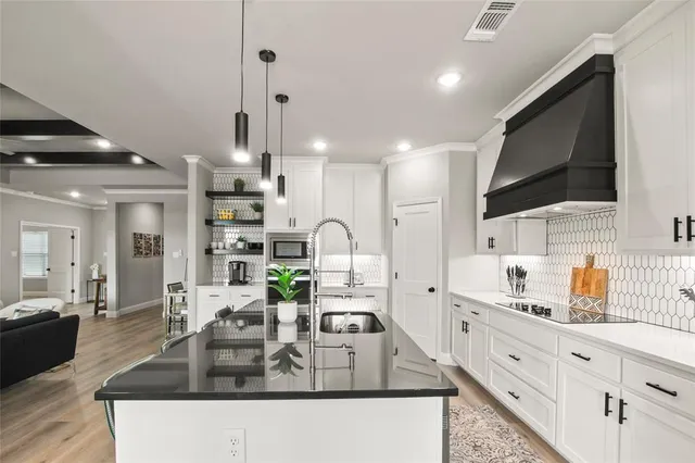 a large kitchen with granite countertop a sink and a stove top oven with wooden floor
