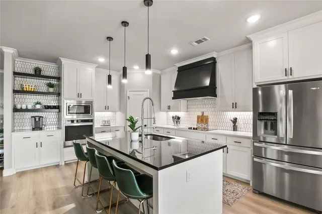 a kitchen with stainless steel appliances kitchen island granite countertop a sink refrigerator and microwave