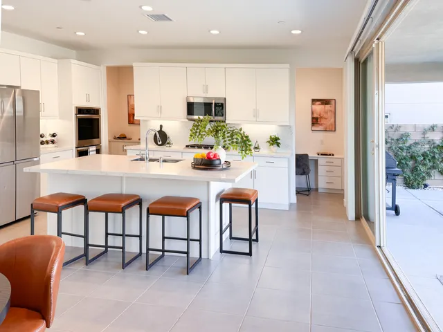 a kitchen with stainless steel appliances granite countertop a dining table chairs and a refrigerator