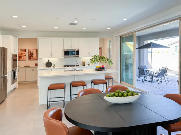 a kitchen with stainless steel appliances kitchen island granite countertop a table chairs microwave and sink