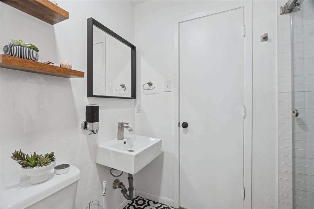 9780 Windy Ridge Road Frisco, TX 75033 - Photo 14 of 25 Bathroom featuring a wall-mounted square sink with a single-handle faucet, a black-framed mirror, and two wood-finish floating shelves