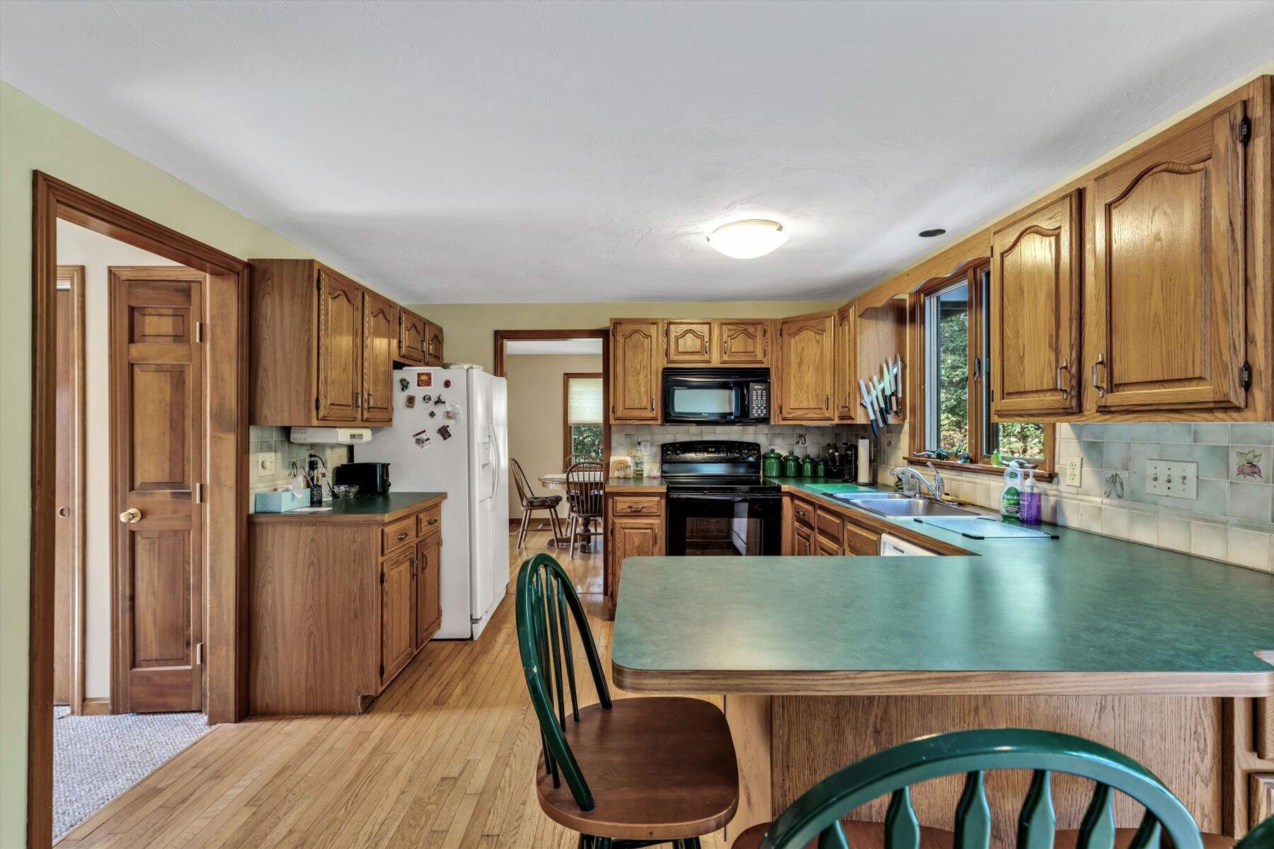 4 Surf Drive Mashpee, MA 02649 - Photo 2 of 22 a kitchen with stainless steel appliances granite countertop a refrigerator a stove top oven a sink dishwasher and wooden cabinets with wooden floor