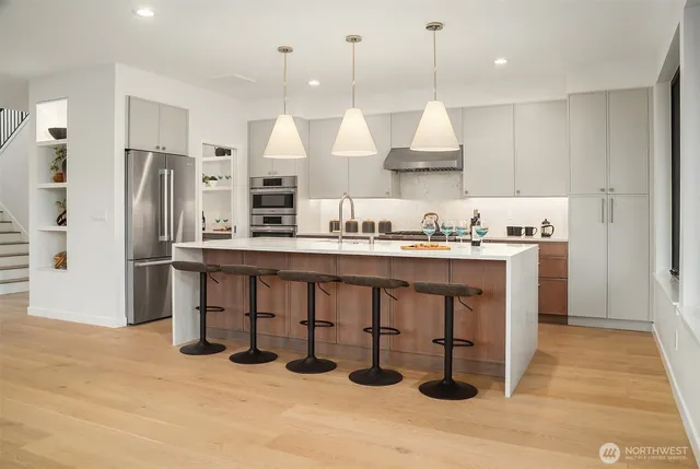 a kitchen with stainless steel appliances a sink a refrigerator and chairs