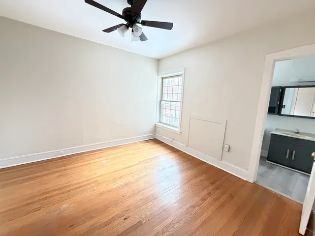 an empty room with wooden floor cabinet and windows