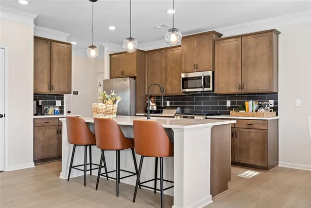 a kitchen with stainless steel appliances a sink a stove a microwave a refrigerator a counter space and cabinets