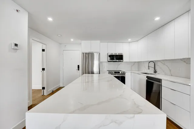 a large white kitchen with stainless steel appliances