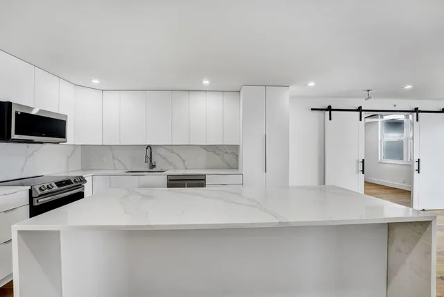 a kitchen with stainless steel appliances a refrigerator a stove a microwave and white cabinets