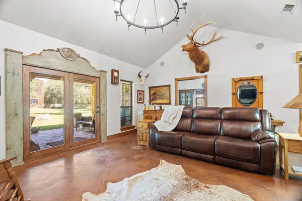 a living room with furniture a chandelier and a floor to ceiling window