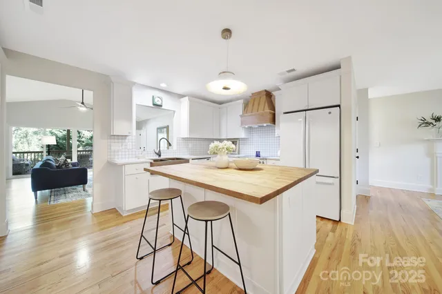 a kitchen with a stove a refrigerator and a dining table with wooden floor