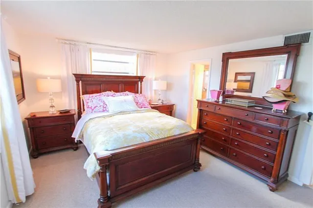 a bed sitting in a bedroom next to a window mirror and dresser