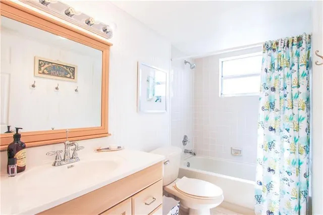 a bathroom with a bathtub shower sink vanity mirror and toilet