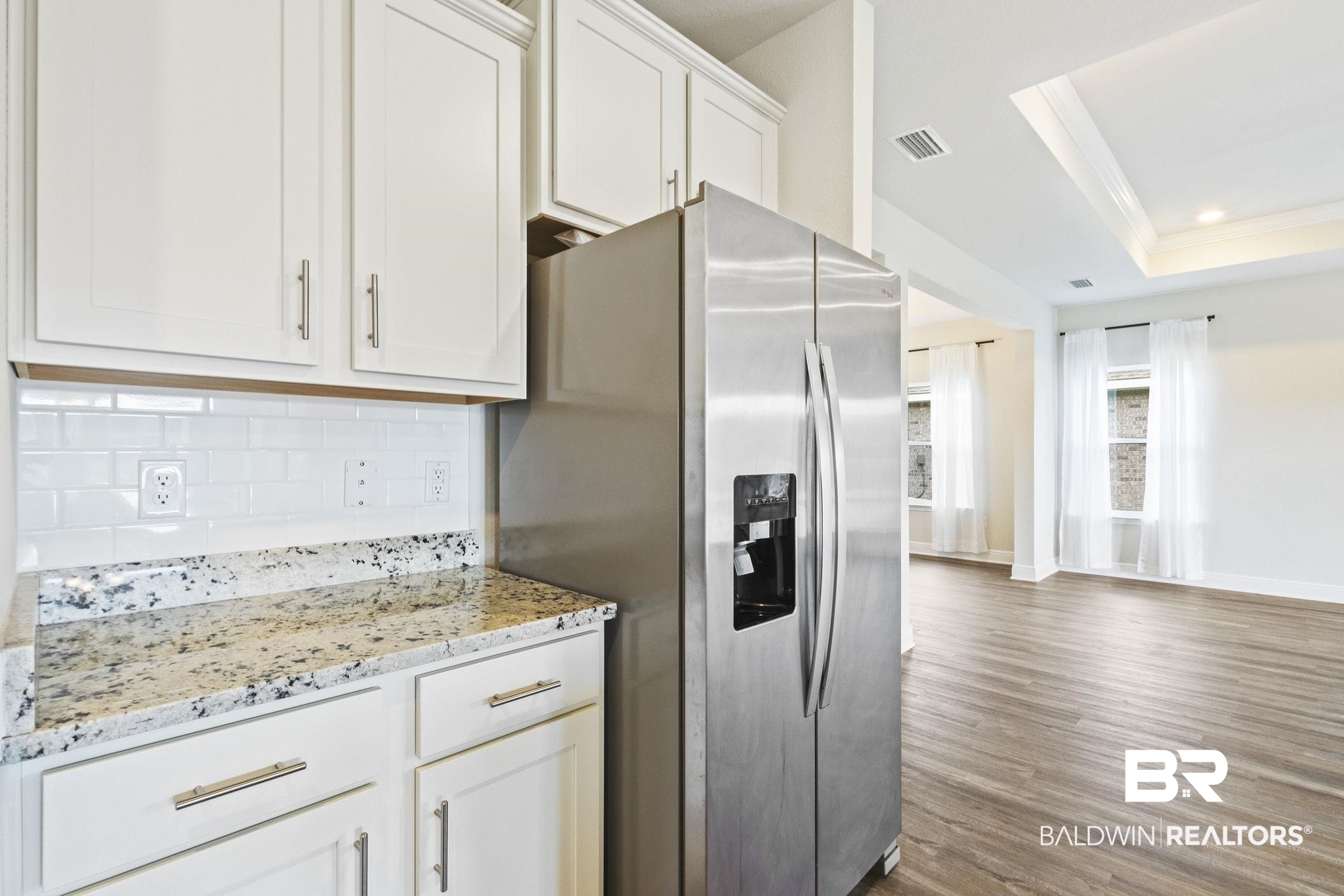 11303 Genuine Risk Circle Daphne, AL 36526 - Photo 34 of 100 Kitchen featuring a raised ceiling, backsplash, dark hardwood / wood-style flooring, white cabinets, and stainless steel fridge with ice dispenser