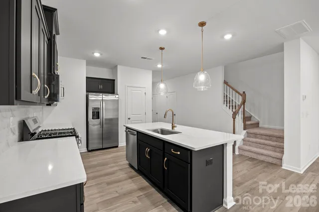 a kitchen with a sink a counter top space stainless steel appliances and cabinets