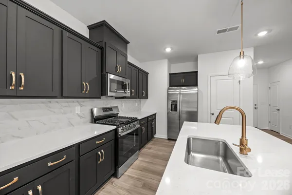 a kitchen with granite countertop a sink stainless steel appliances and cabinets
