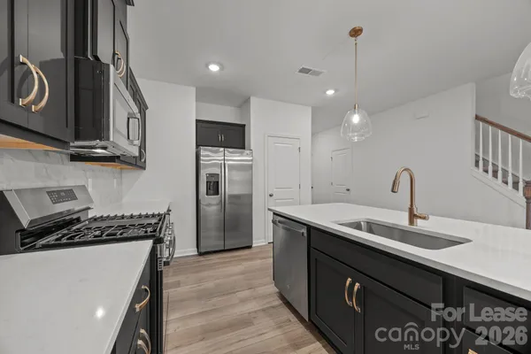 a kitchen with stainless steel appliances granite countertop a sink a stove and a wooden floors