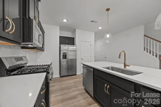 a kitchen with stainless steel appliances granite countertop a sink a stove and a wooden floors