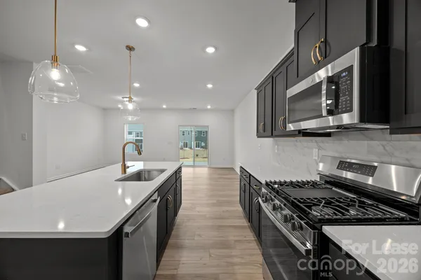 a kitchen with stainless steel appliances granite countertop a sink a stove top oven a counter space and cabinets