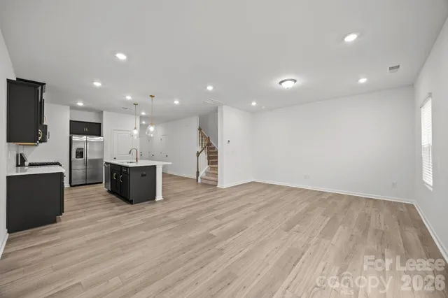 a large kitchen with stainless steel appliances a large counter top and wooden floors