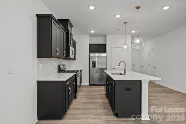 a kitchen with stainless steel appliances granite countertop a sink a stove and a wooden floors