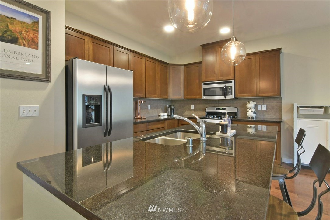 16517 2nd Park Southeast Bothell, WA 98012 - Photo 6 of 22 a kitchen with stainless steel appliances granite countertop a refrigerator a stove a microwave oven a sink with island and chairs
