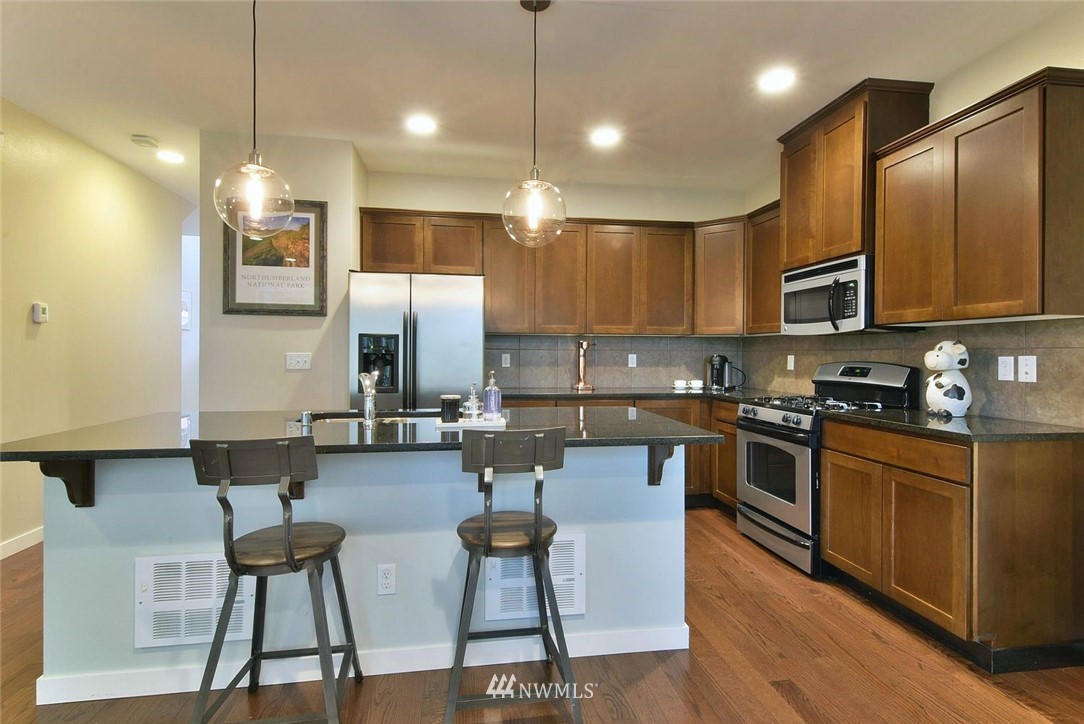 16517 2nd Park Southeast Bothell, WA 98012 - Photo 8 of 22 a kitchen with stainless steel appliances granite countertop a stove top oven a sink dishwasher a dining table and chairs with wooden floor