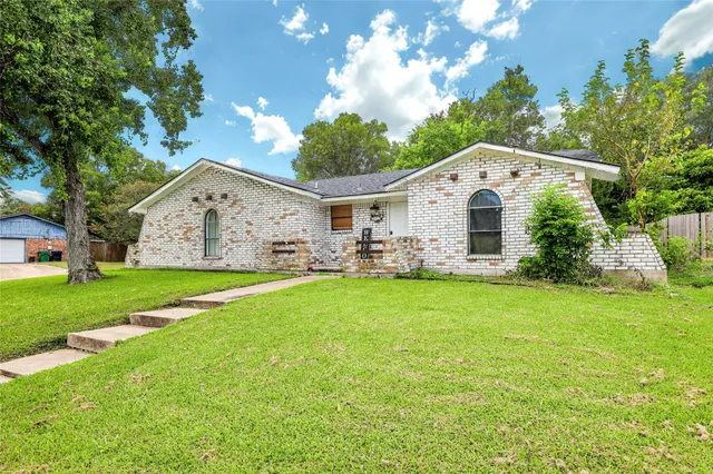 a view of a white house with a big yard plants and large trees