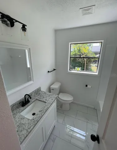 a bathroom with a granite countertop sink a toilet and a mirror