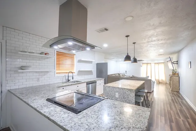 a kitchen with granite countertop a stove and white cabinets