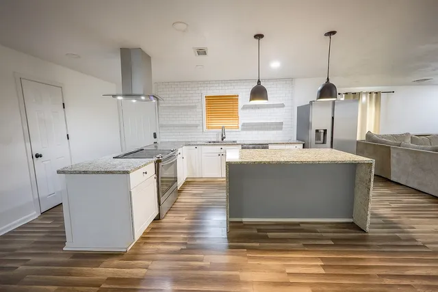 a large kitchen with kitchen island a sink a counter top space and stainless steel appliances