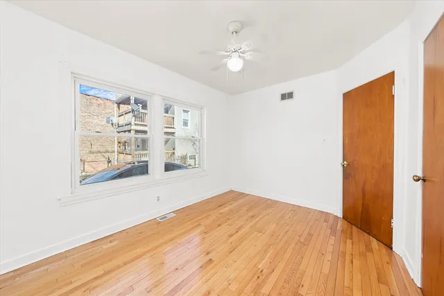 a view of empty room with wooden floor and fan