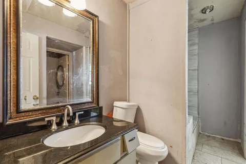 a bathroom with a granite countertop sink a toilet and a mirror